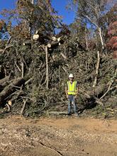 6-foot tall man beside large debris pile